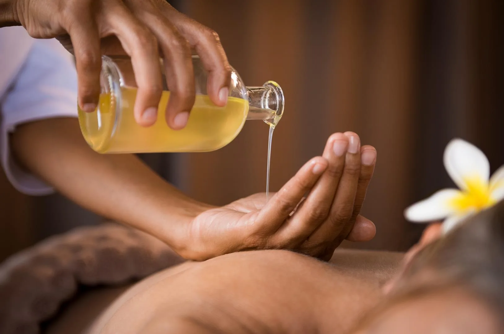 Therapeutin gießt Massageöl im Spa